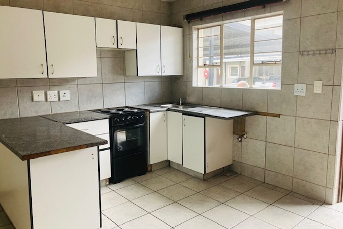 A functional kitchen featuring white cabinetry, tiled splashbacks, and a freestanding oven. The space is empty and ready for cosmetic updates.