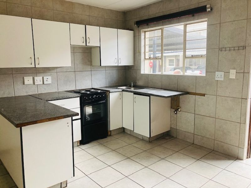 A functional kitchen featuring white cabinetry, tiled splashbacks, and a freestanding oven. The space is empty and ready for cosmetic updates.