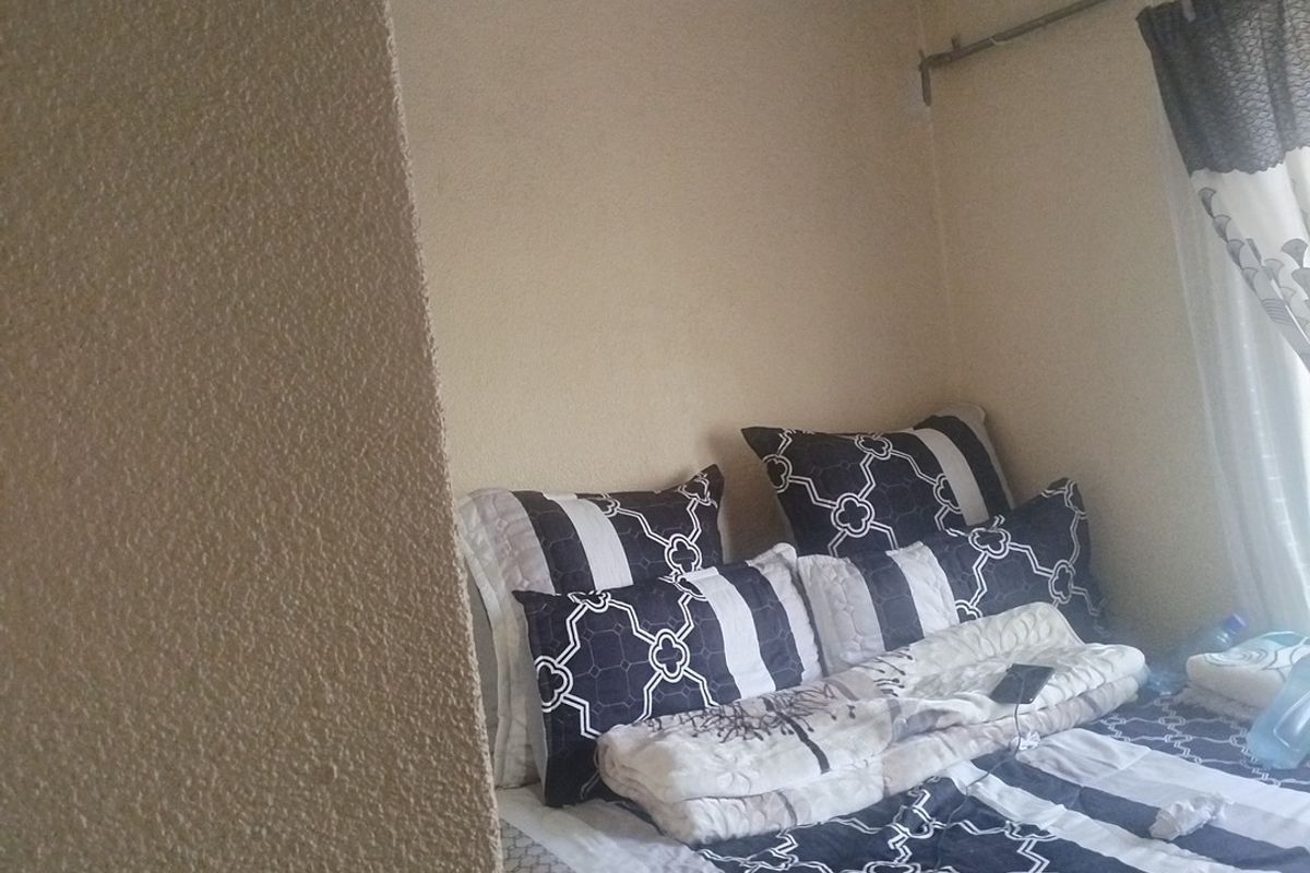 A bedroom featuring textured wall finishes and a curtain rod, providing a functional sleeping space.