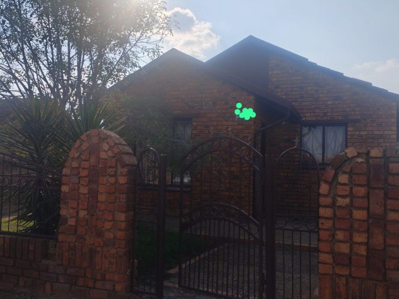 Front view of a face brick house featuring a secure wrought iron gate and brick boundary wall.