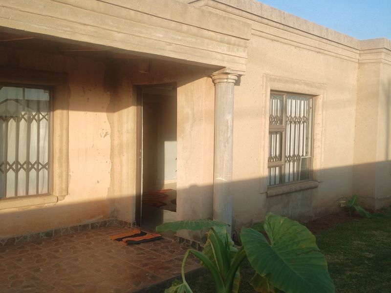 Front facade of a single-story house featuring a tiled entrance patio, security gates on windows, and concrete columns.