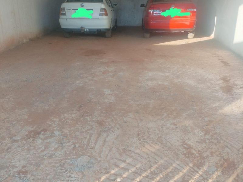 A spacious, unfinished garage area with concrete flooring and walls, providing ample room for vehicle storage.
