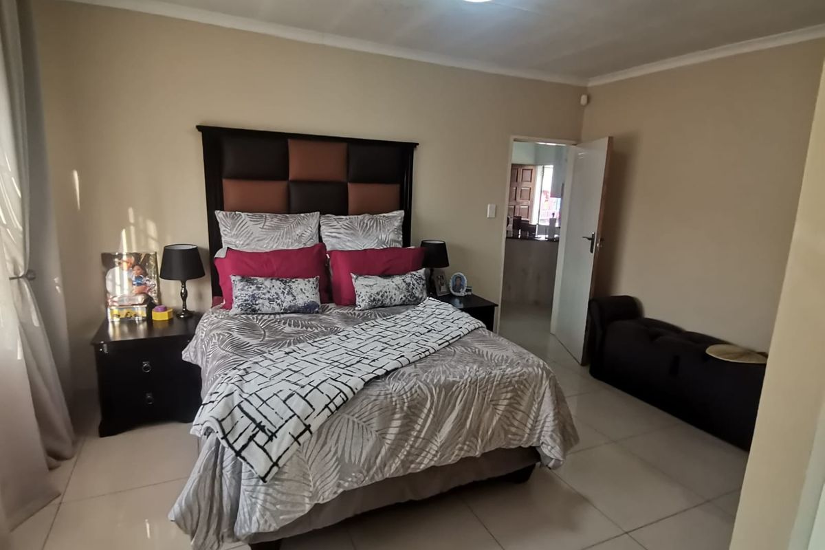 A well-maintained bedroom featuring neutral wall tones, tiled flooring, and a coved ceiling with central lighting.