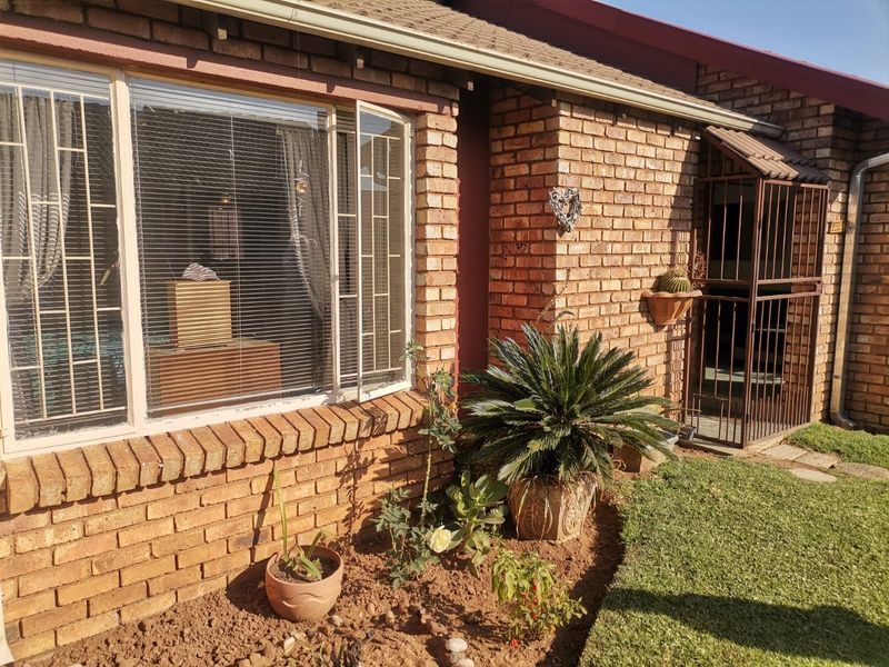 Front exterior view of a face brick townhouse featuring security bars on windows and a secure entrance gate.