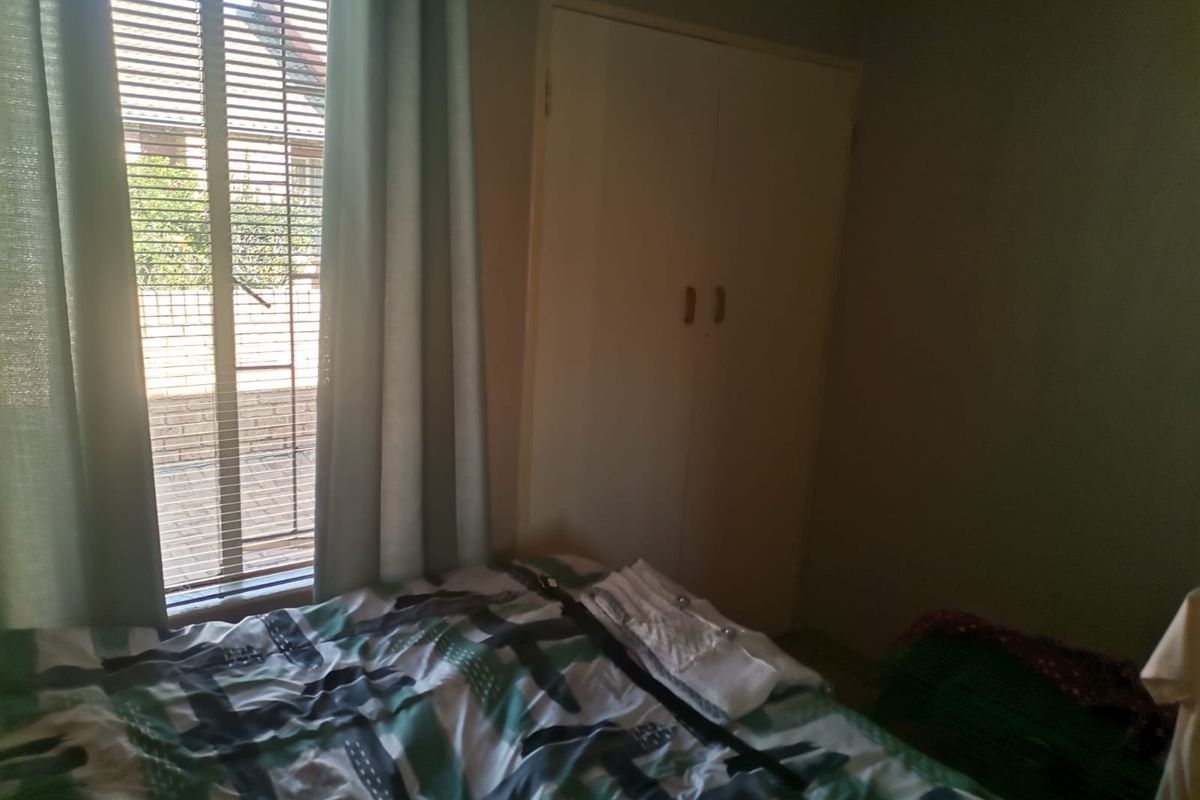 A bedroom featuring a built-in wardrobe and venetian blinds, providing functional storage and natural light control.