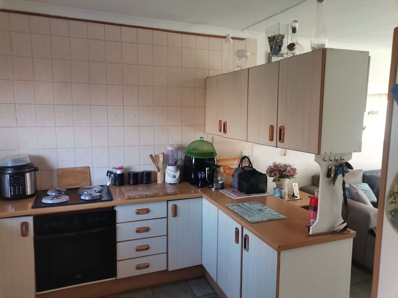 A functional kitchen featuring laminate cabinetry, laminate countertops, and ceramic wall tiling, equipped with a built-in oven and electric hob.