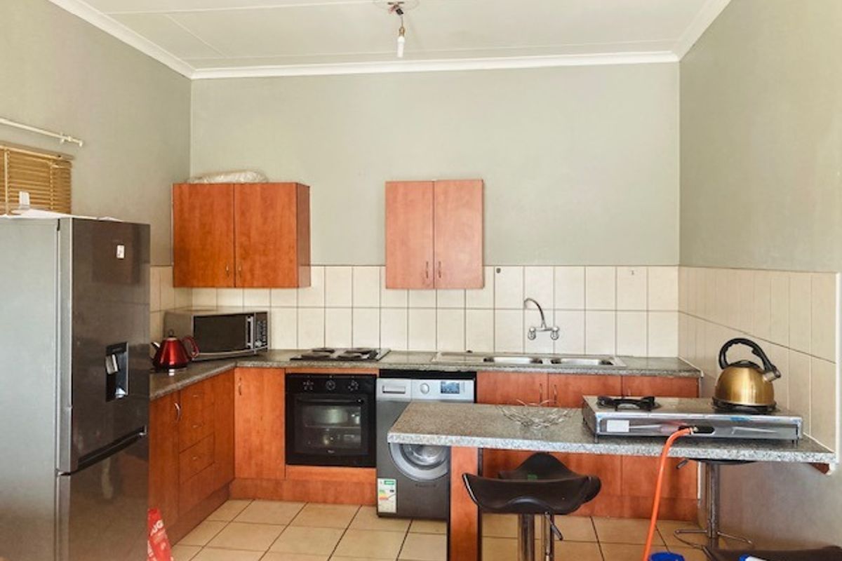 A functional kitchen featuring built-in cabinetry, a breakfast bar, integrated oven and hob, and tiled backsplash, offering a practical layout for daily use.