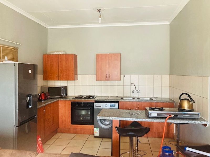 A functional kitchen featuring built-in cabinetry, a breakfast bar, integrated oven and hob, and tiled backsplash, offering a practical layout for daily use.