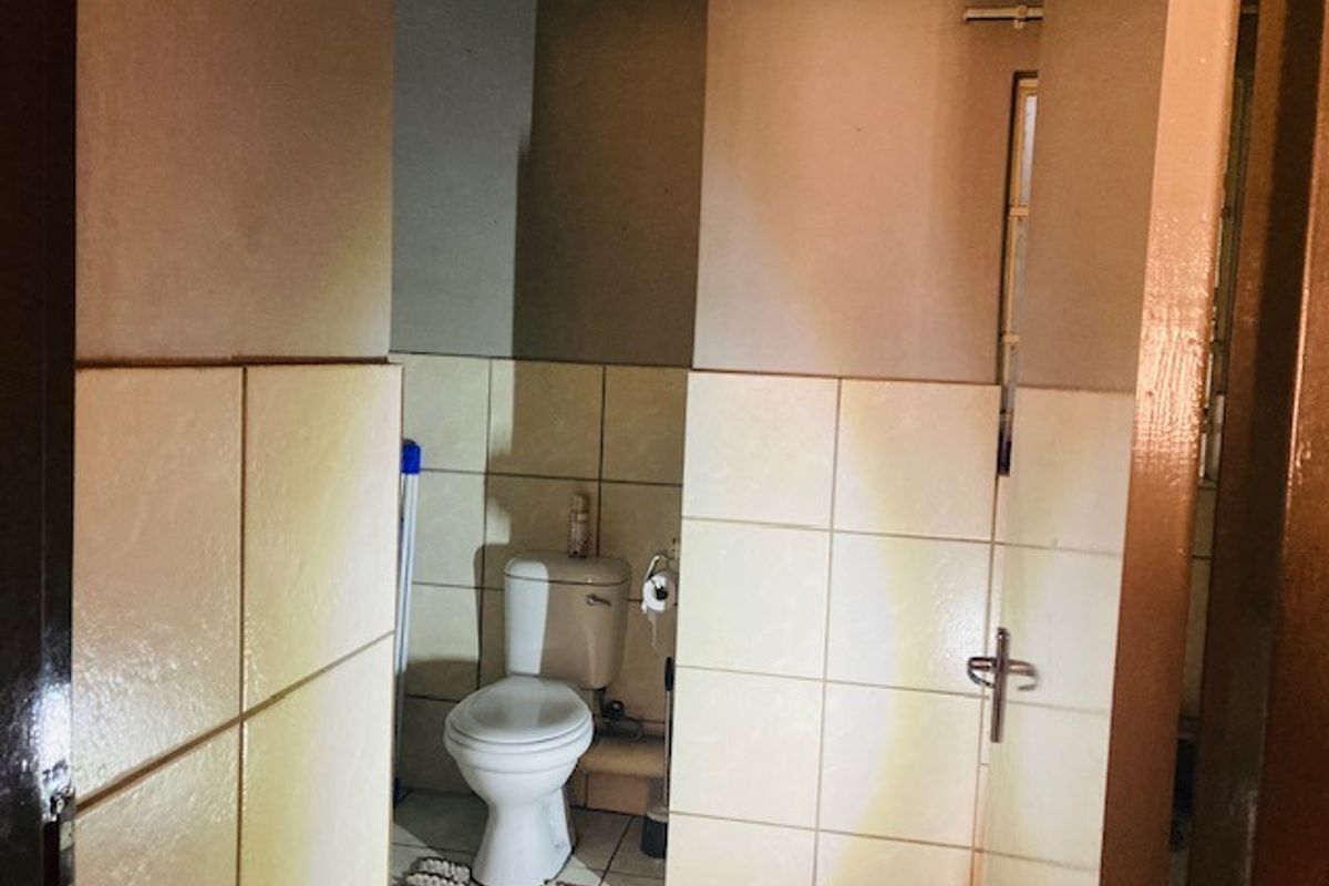 A functional bathroom featuring a standard toilet, tiled walls, and tiled flooring, providing a basic and practical layout.