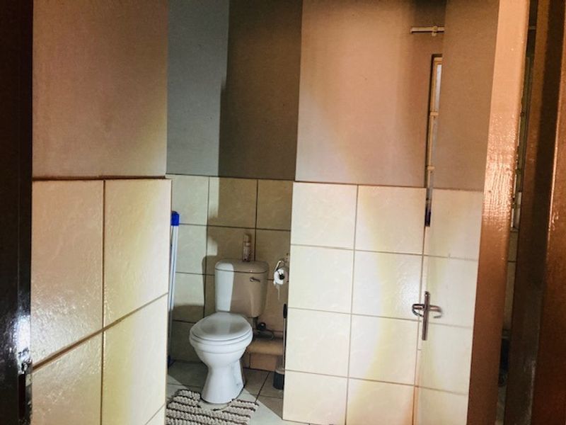 A functional bathroom featuring a standard toilet, tiled walls, and tiled flooring, providing a basic and practical layout.