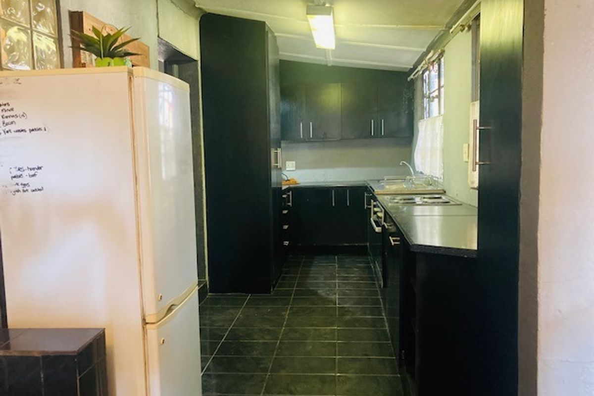 A functional kitchen featuring dark cabinetry, tiled flooring, and a built-in hob, offering a practical layout with potential for modern cosmetic updates.