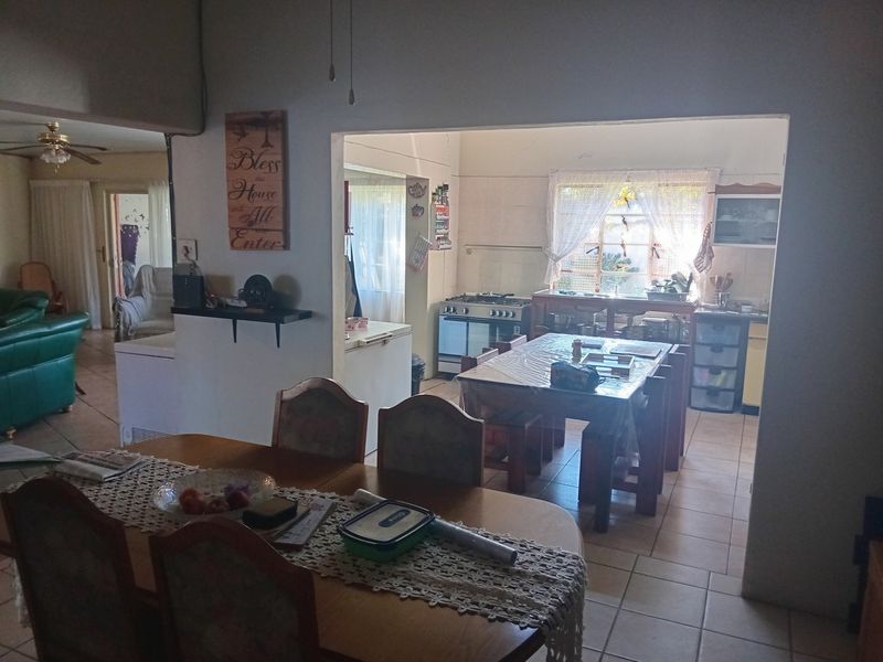 Open-plan living and dining area featuring tiled flooring, a functional kitchen with a gas stove, and direct access to adjacent living spaces.