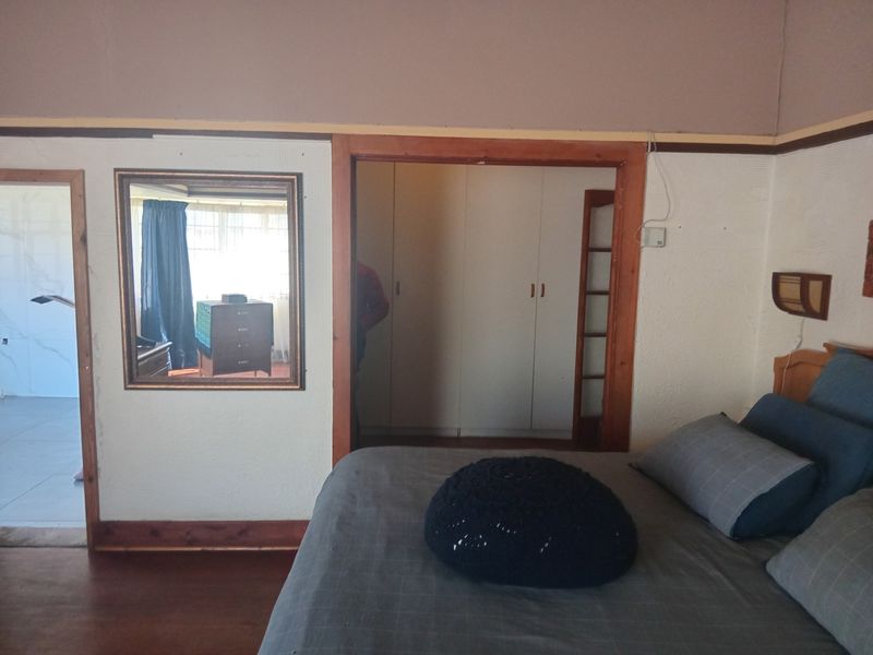 A bedroom featuring built-in cupboards, wooden door frames, and skirting boards, showing signs of wear on the walls and finishes.