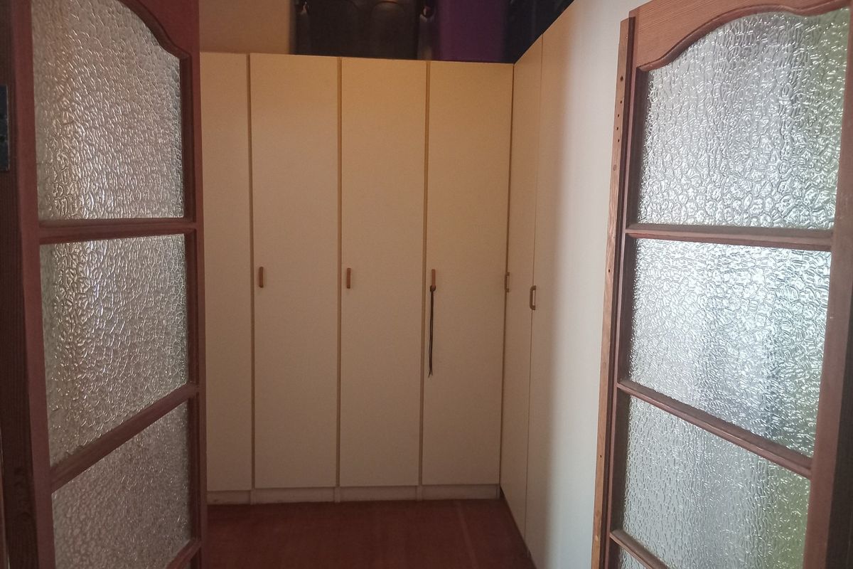 A bedroom featuring extensive built-in cabinetry and traditional timber-framed doors with textured glass panels.