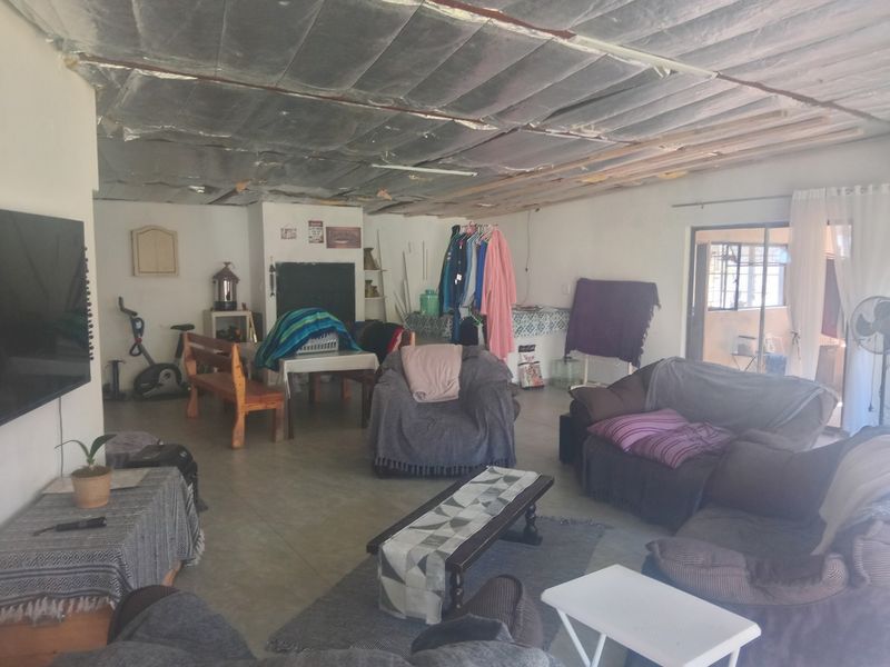Spacious living area featuring tiled flooring and a sliding glass door, currently requiring ceiling completion and finishing to improve the overall aesthetic.