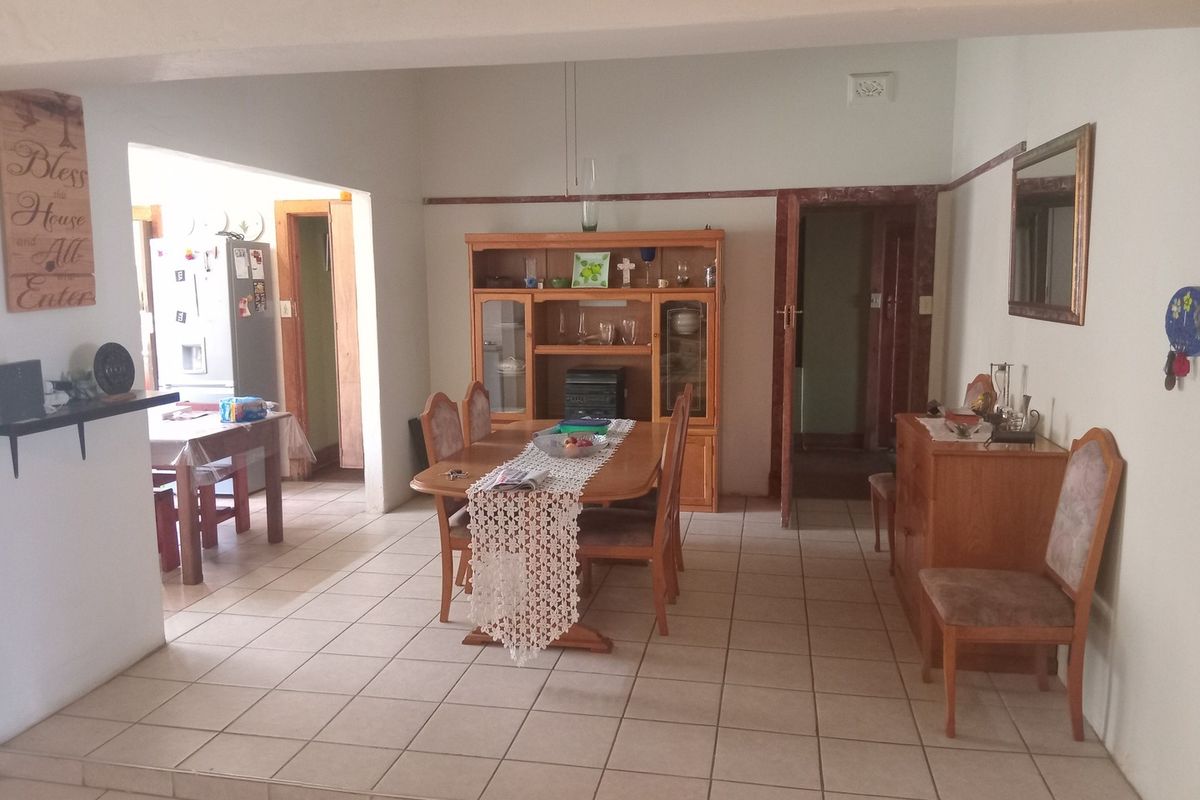Open plan dining area featuring ceramic floor tiles and an archway leading to the kitchen, offering a functional layout for family living.
