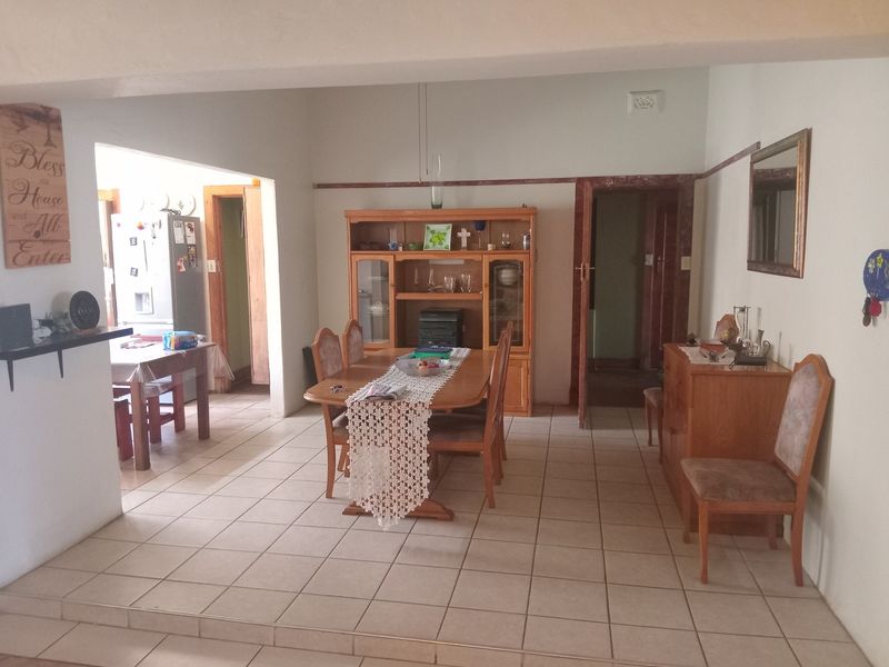 Open plan dining area featuring ceramic floor tiles and an archway leading to the kitchen, offering a functional layout for family living.