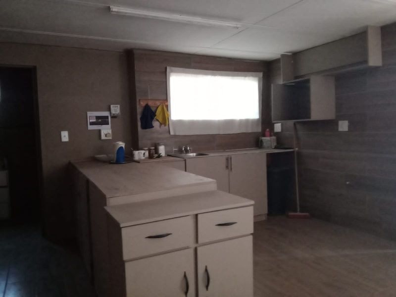 A basic, empty kitchen area featuring built-in cabinetry, a sink, and tiled wall finishes, offering a blank canvas for potential renovation.