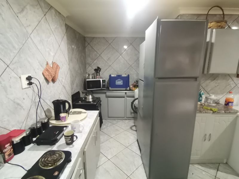 A functional kitchen featuring tiled walls and flooring, built-in cabinetry, and a stove, offering a practical layout for daily meal preparation.