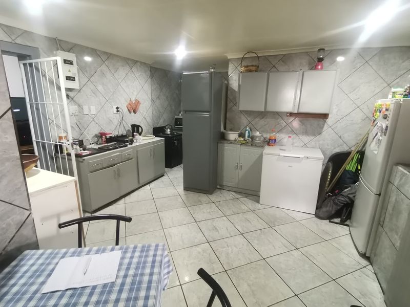 A functional kitchen featuring tiled walls and flooring with built-in cabinetry and ample counter space, offering a practical layout for daily meal preparation.