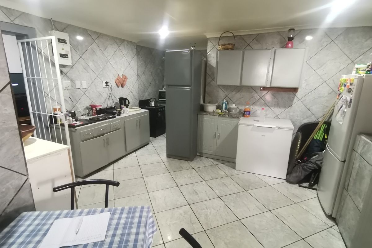 A functional kitchen featuring tiled walls and flooring with built-in cabinetry and ample counter space, offering a practical layout for daily meal preparation.