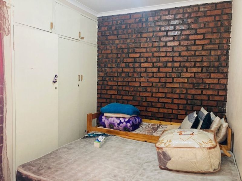 Bedroom featuring a prominent exposed brick feature wall and ample built-in cupboard storage space.