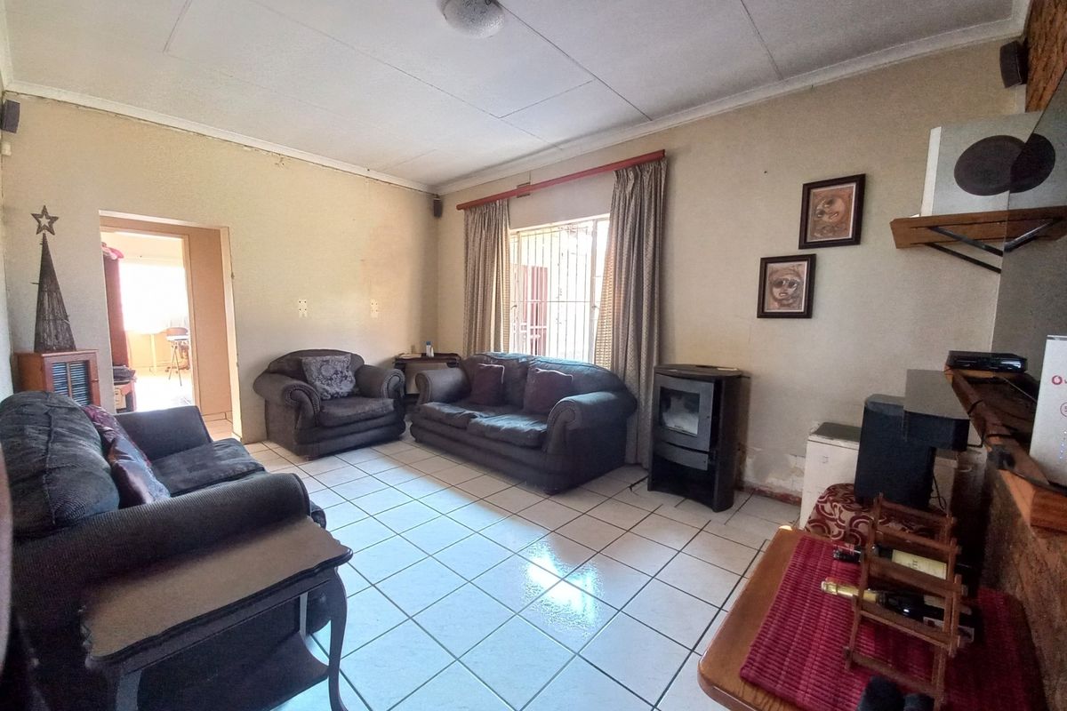Living room featuring tiled flooring and a freestanding fireplace, with visible wear to the wall finishes near the hearth area.