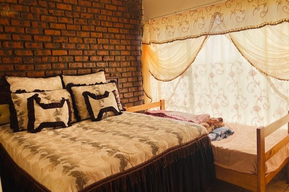 A bedroom featuring an exposed brick feature wall and tiled flooring, providing a rustic aesthetic foundation for potential interior updates.