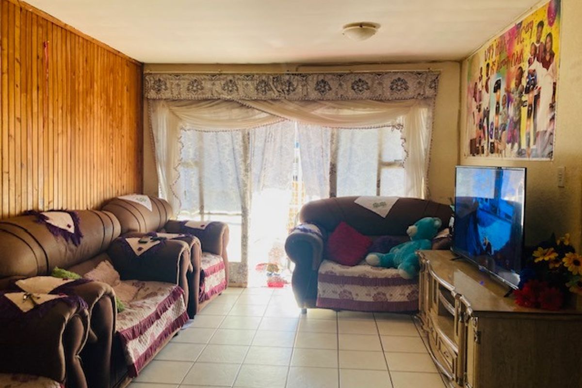 A living room featuring timber wall paneling, tiled flooring, and a sliding glass door providing access to the exterior.