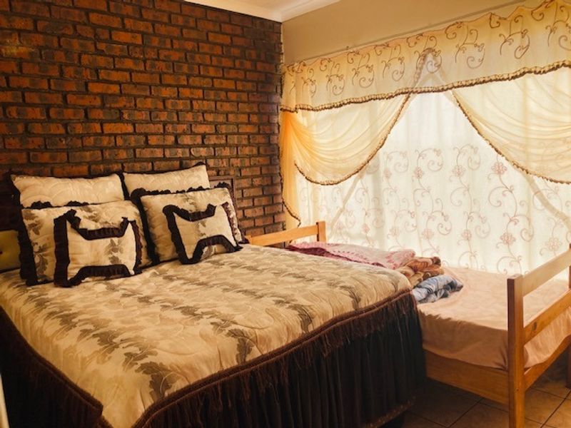 A bedroom featuring an exposed brick feature wall and tiled flooring, providing a rustic aesthetic foundation for potential interior updates.