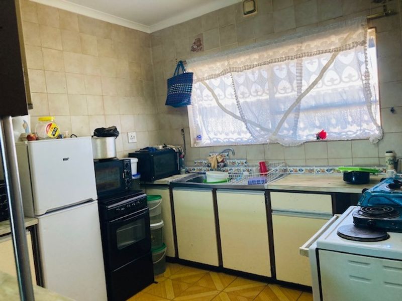 A dated kitchen featuring original cabinetry, tiled splashbacks, and a functional sink area, offering significant potential for a modern renovation.