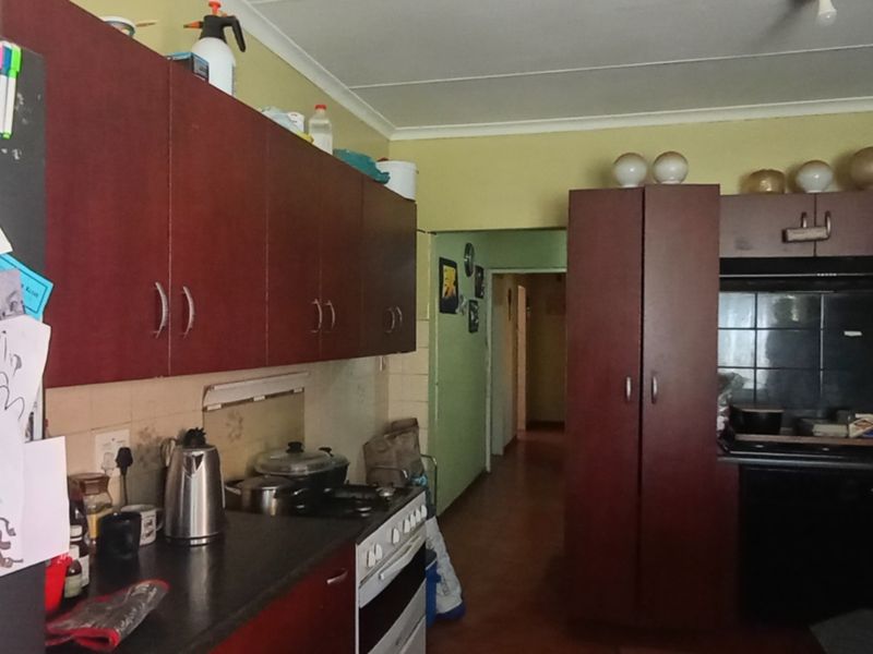 A functional kitchen featuring dark wood-look cabinetry, laminate countertops, and a tiled splashback, offering a practical layout with potential for modern cosmetic updates.