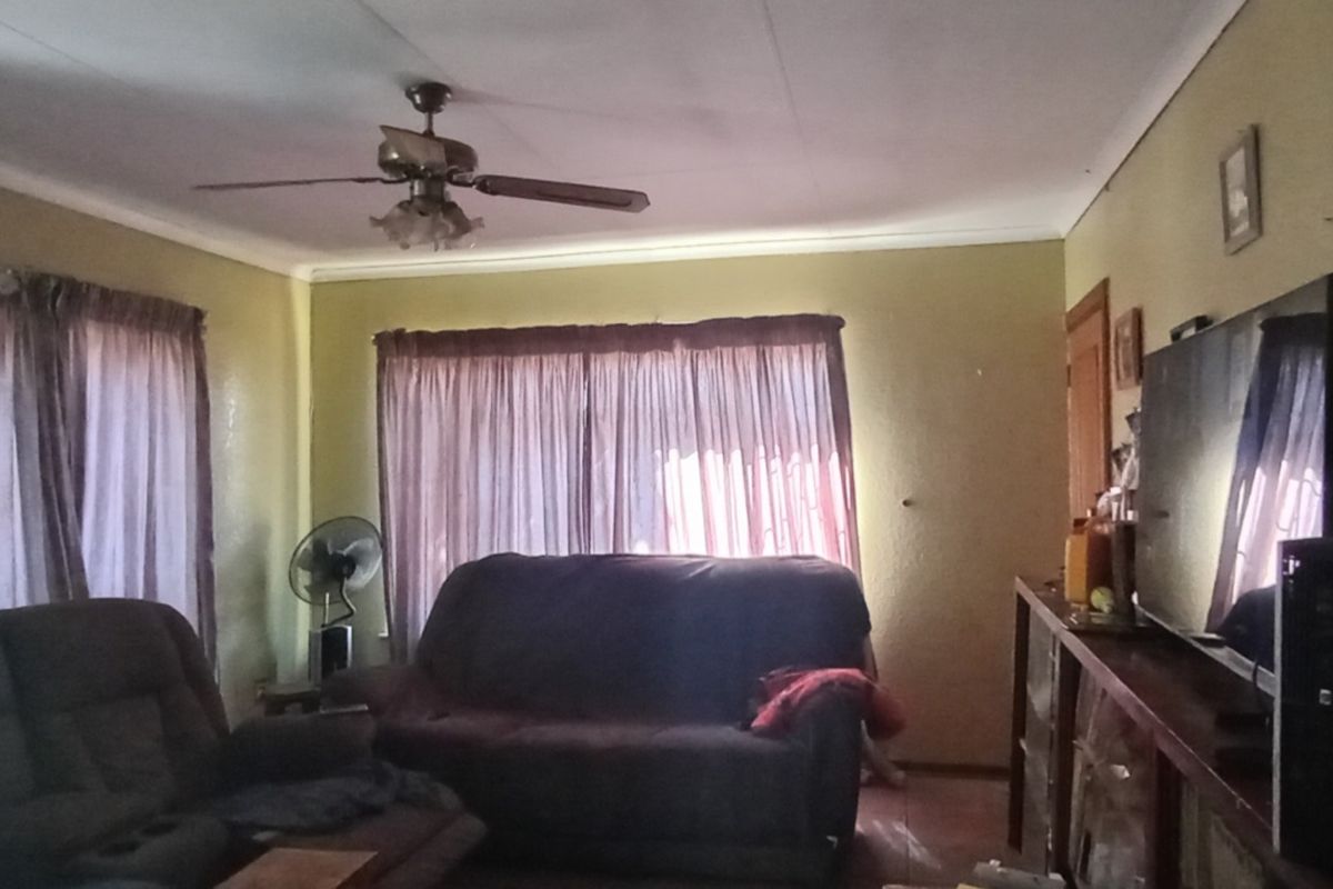 A living room featuring a ceiling fan and coved cornicing, requiring cosmetic updates to improve the overall aesthetic and appeal.