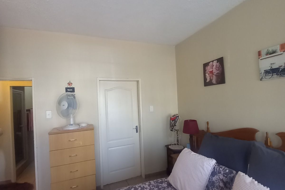 A bedroom featuring tiled flooring and a neutral wall finish, with an adjacent doorway leading to an en-suite bathroom.