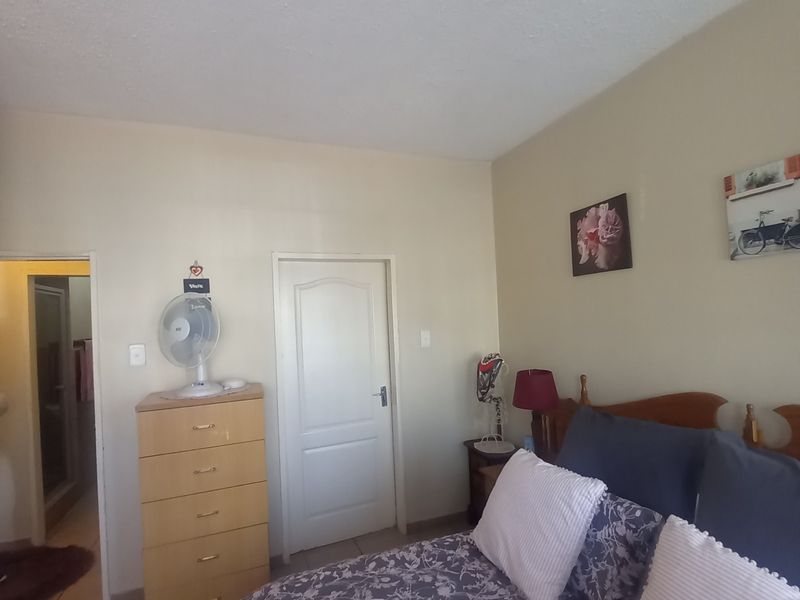 A bedroom featuring tiled flooring and a neutral wall finish, with an adjacent doorway leading to an en-suite bathroom.