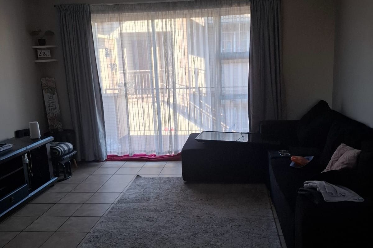 A living room featuring tiled flooring and a large sliding glass door that provides access to an outdoor balcony area.