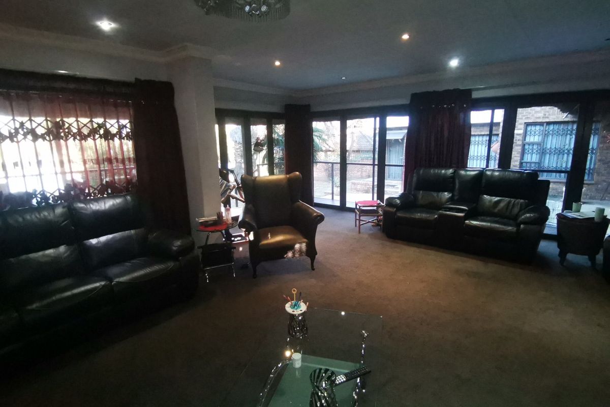 Spacious living room featuring recessed lighting, a crystal chandelier, and large glass sliding doors providing access to the exterior.