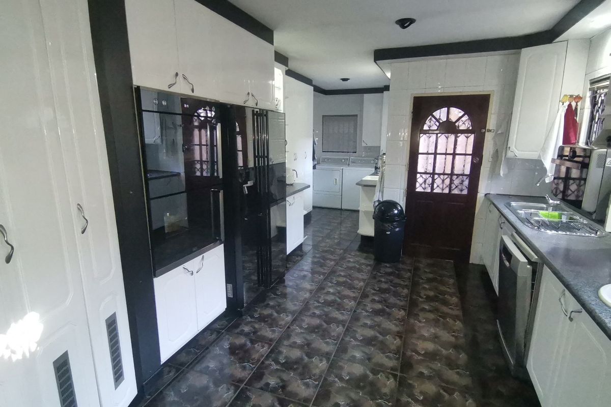 A functional kitchen featuring built-in cabinetry, integrated oven, stainless steel sink, and tiled flooring with direct access to the exterior.