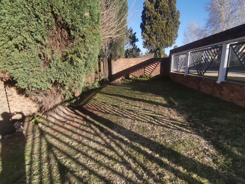 A private garden area featuring a brick boundary wall, decorative metal fencing, and mature trees, offering a secluded outdoor space.