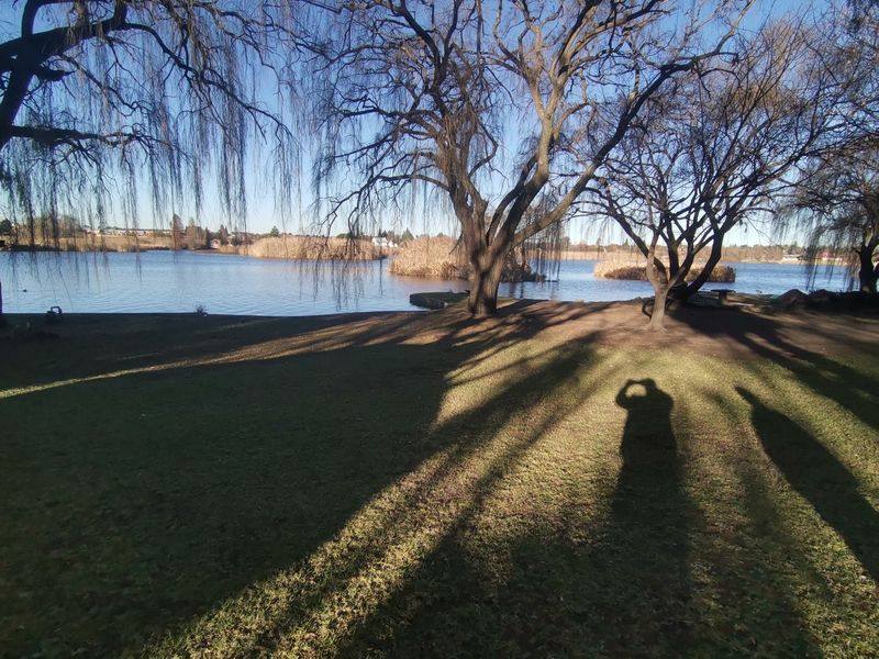 A scenic view of a tranquil lake surrounded by mature trees, offering a peaceful outdoor setting.