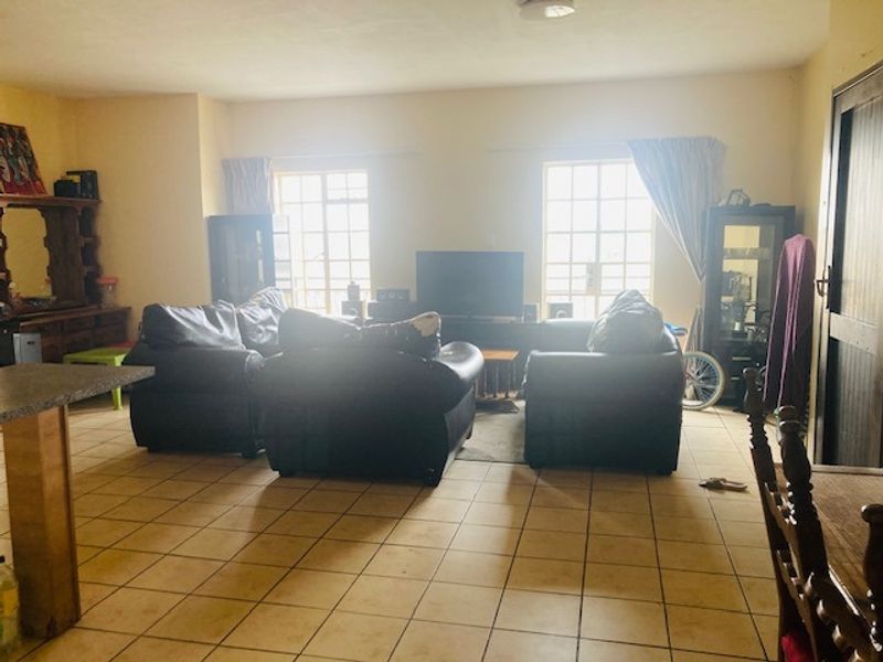 A spacious living room featuring tiled flooring and large windows that provide ample natural light.