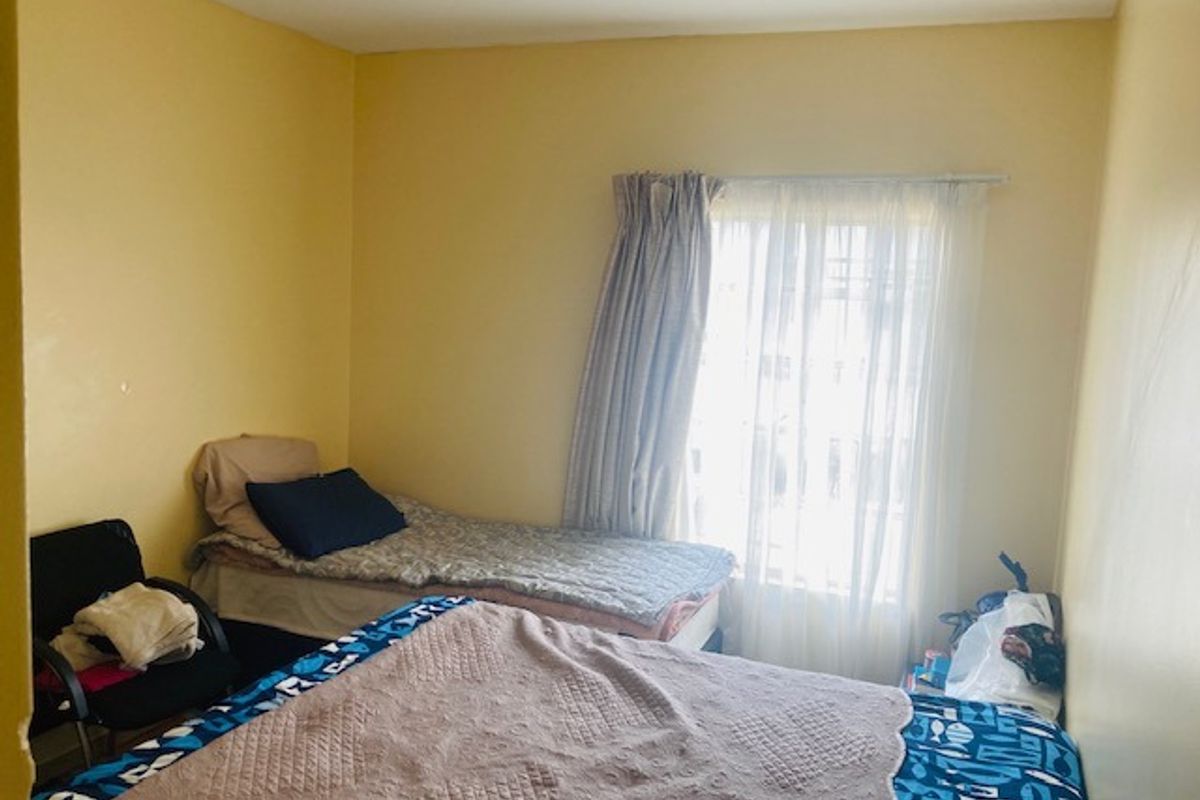 A functional bedroom featuring yellow walls and a window with installed curtain rods and curtains.