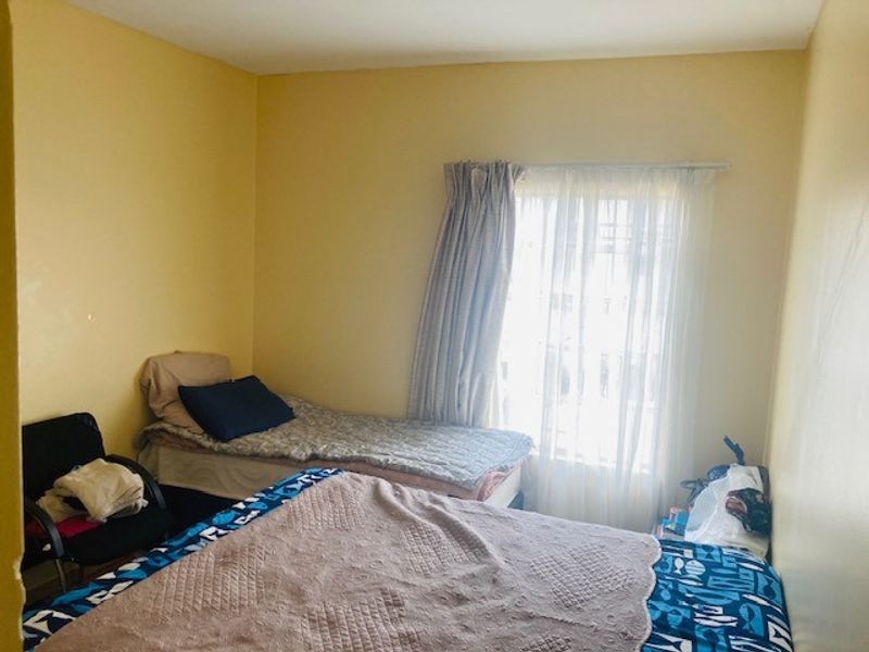 A functional bedroom featuring yellow walls and a window with installed curtain rods and curtains.
