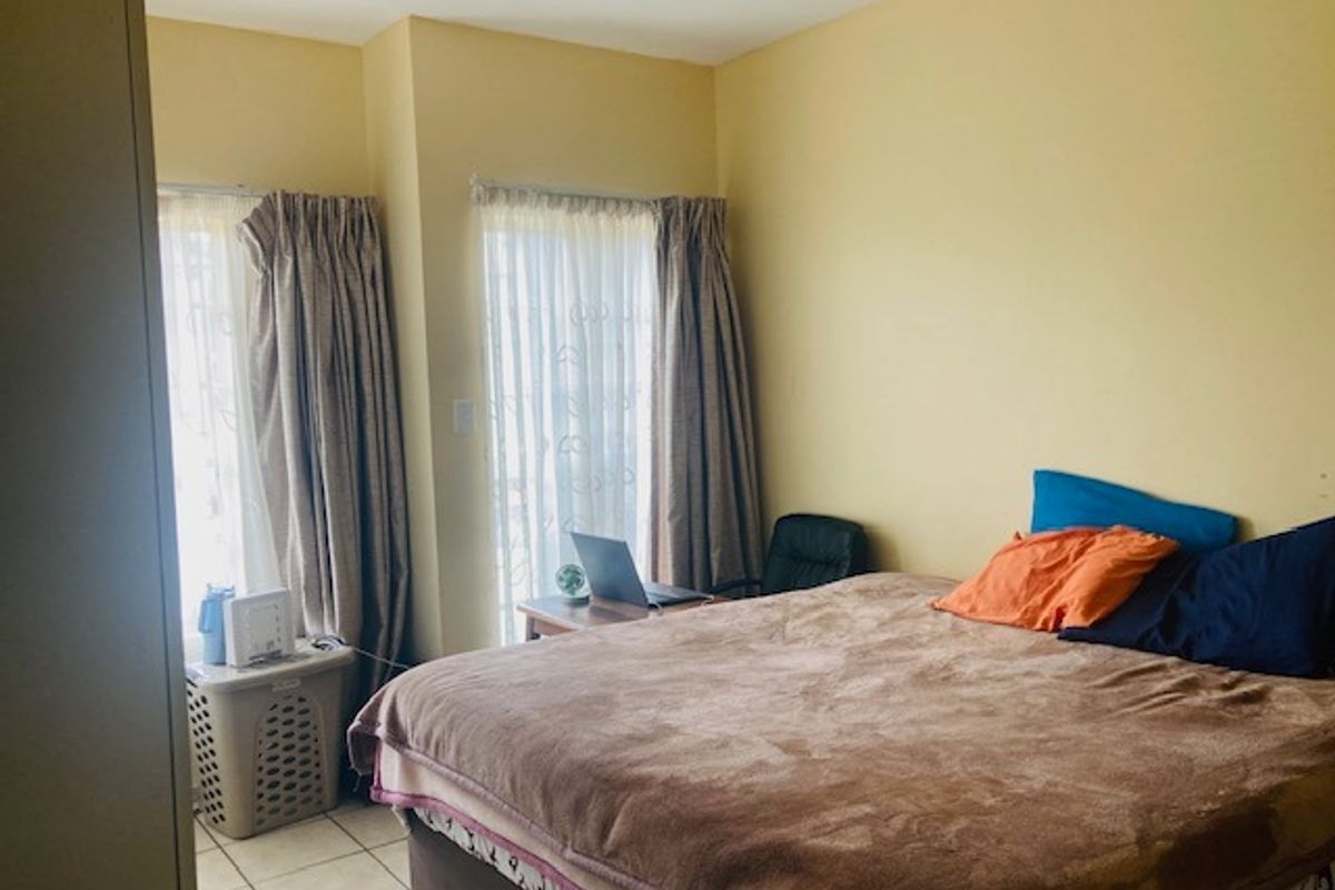 A bedroom featuring tiled flooring and sliding glass doors that provide natural light.