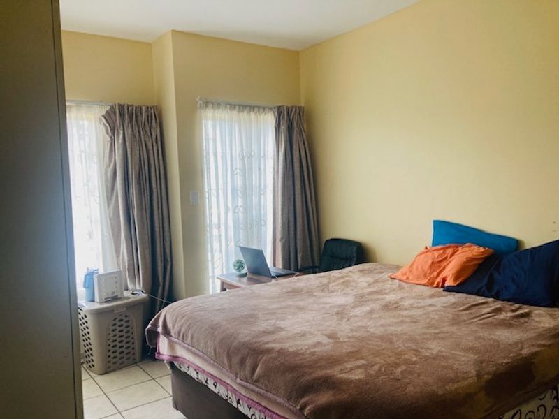 A bedroom featuring tiled flooring and sliding glass doors that provide natural light.