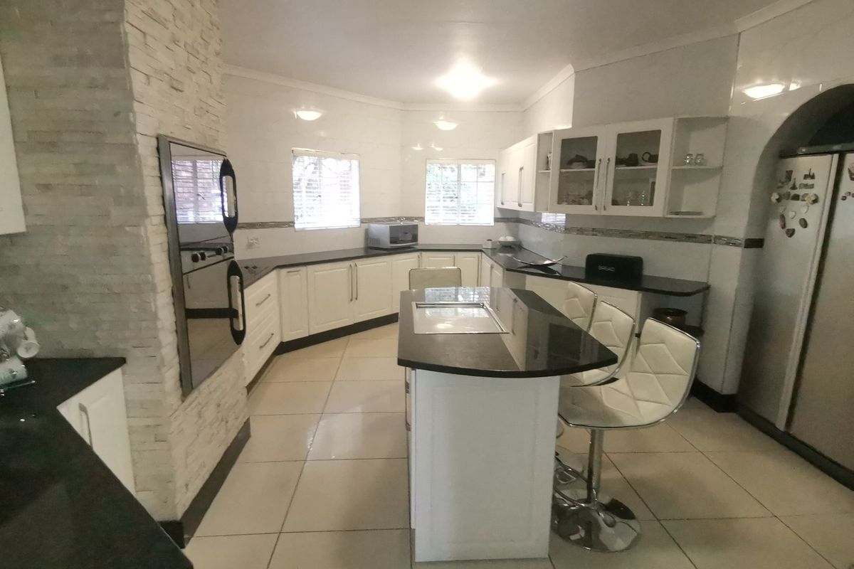 Spacious kitchen featuring a central island, granite countertops, built-in oven, and a distinctive stacked stone feature wall with ample cabinetry.