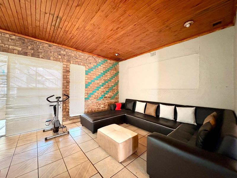 Living room featuring exposed brick walls, tiled flooring, and a timber tongue and groove ceiling.