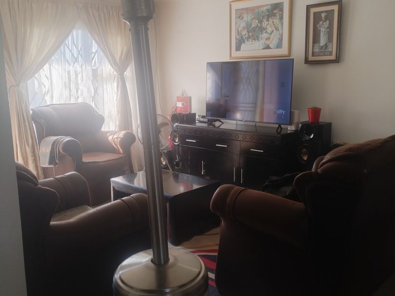 A living room area featuring tiled flooring and natural light through window curtains.