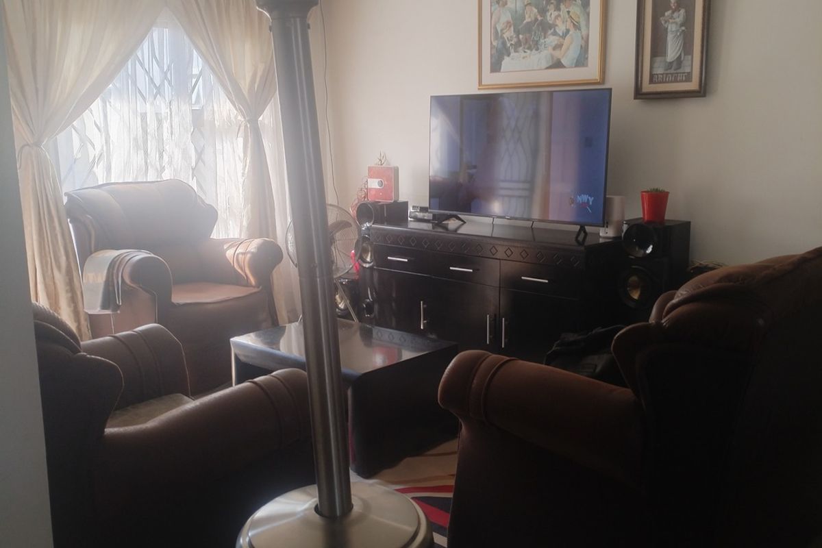 A living room area featuring tiled flooring and natural light through window curtains.