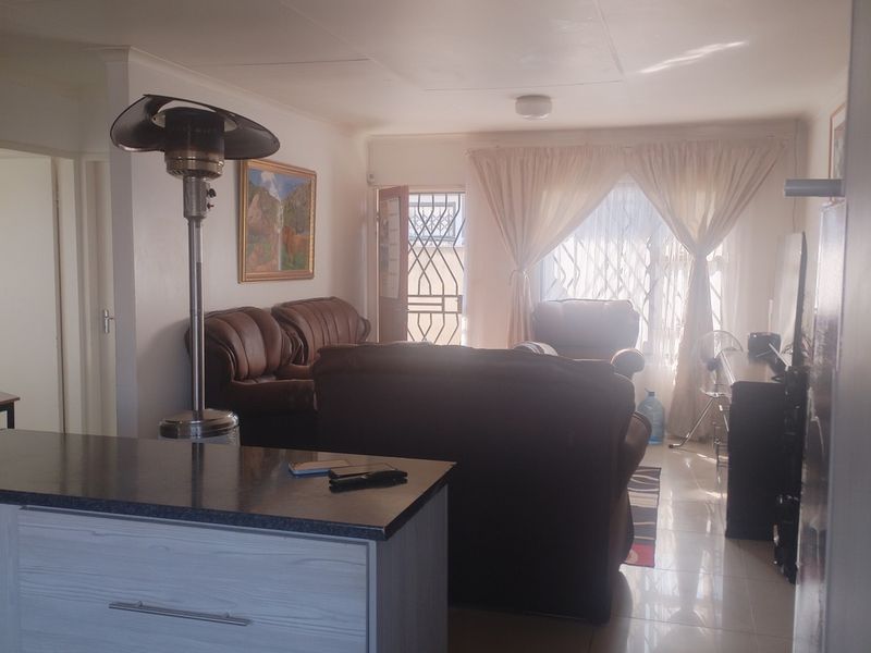 Open plan living area featuring a kitchen island with stone countertop and tiled flooring, leading to an exterior entrance with security gate.